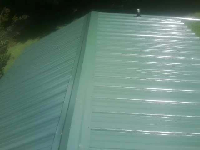 New green metal panels meeting at the ridge of a roof — Flat Roof Repair work by our crew in Darlington