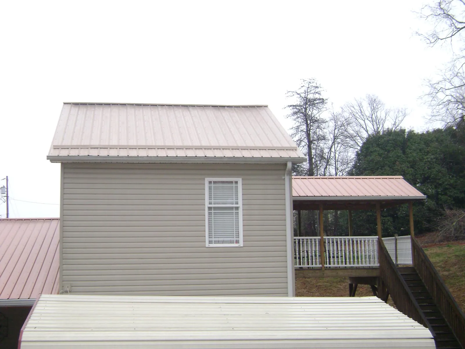 Tan metal roofs on a two story addition and attached porch, from a Roof Replacement job in Darlington